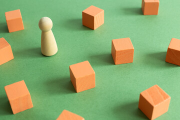 Group of coral blocks and one different wooden human figure on green background. Different opinion, direction, idea, innovation concept