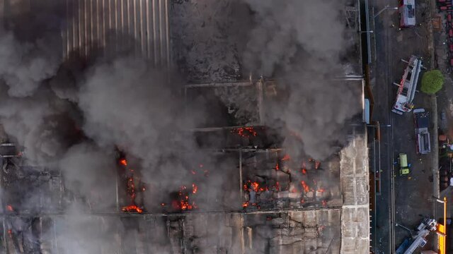 Aerial view above a industrial fire, firetrucks on side - top down, drone shot