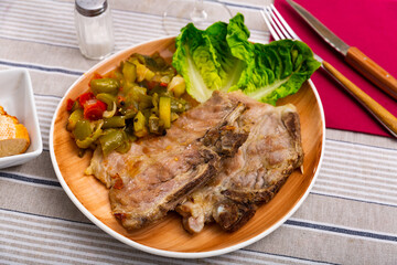 Juicy roast pork on a plate with a side dish of stewed vegetables, garnished with fresh lettuce...