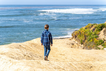 Boy looking at ocean from cliff