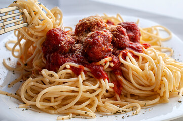side view of spaghetti and meatballs with tomato and garlic salsa and a fork on the side, concept of homemade meals