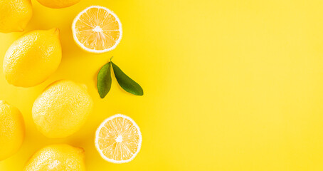 Summer composition made from oranges, lemon and green leaves on pastel yellow background. Fruit minimal concept. Flat lay, top view, copy space.