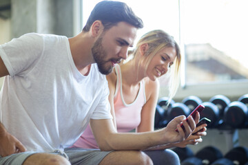 Couple of men women use smartphone talking together after working out