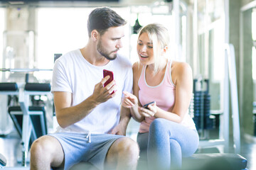 Obraz premium Couple of men women use smartphone talking together after working out