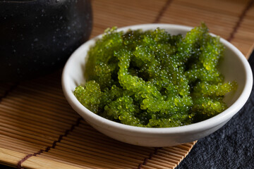 Oval sea grapes seaweed, Close up Green Caviar on dark background