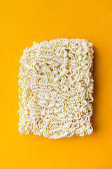 Dry noodle with chopsticks at yellow background. Copy space