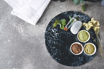 Dry henna powder in bowls and bottle of essential oil on grunge background