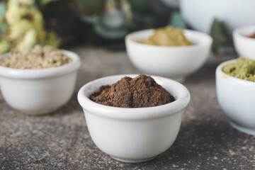 Dry henna powder in bowls on grunge background, closeup