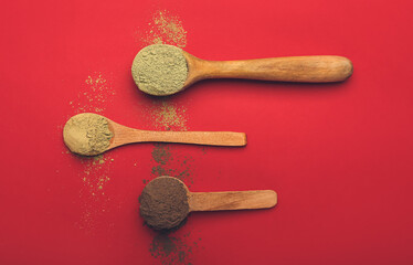 Dry henna powder in spoons on color background