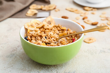 Bowl with tasty granola on grunge background