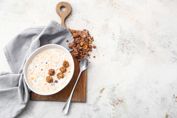 Tasty granola with milk on light background