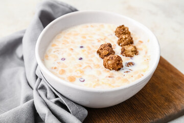 Tasty granola with milk on light background