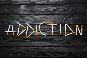 Word ADDICTION made of cigarettes on wooden background