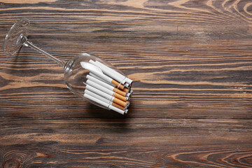 Glass with many cigarettes on wooden background. Concept of addiction