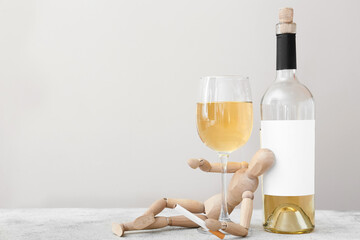 Wooden mannequin with cigarette and alcohol on light background. Concept of addiction