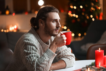 Handsome man drinking hot tea at home on Christmas eve