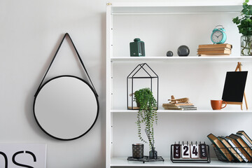 Modern book shelf with decor near light wall