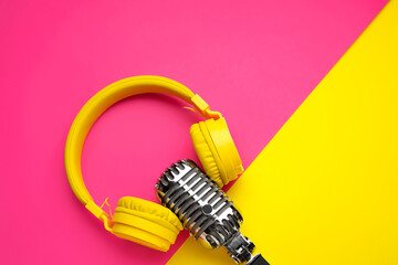 Retro microphone with headphones on color background