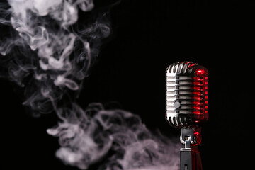 Fototapeta na wymiar Retro microphone on dark background with fume