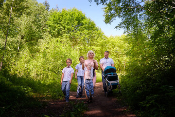 Obraz premium Fun walk of large family in the summer forest. Mother, father, brothers walking in the park or forest on a sunny day