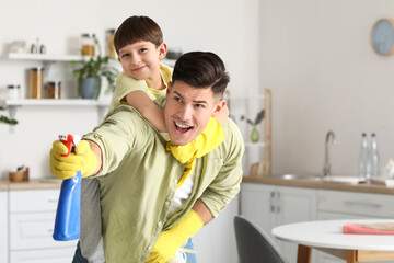 Father and son having fun while cleaning kitchen