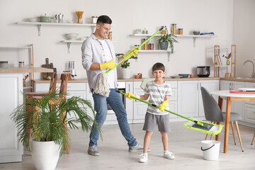 Father and son having fun while mopping floor in kitchen