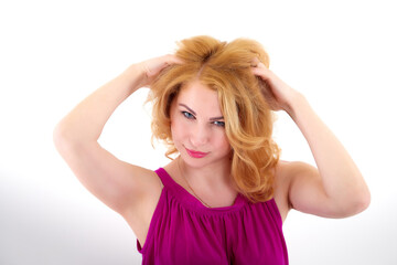 Fototapeta premium Beautiful female model with blonde long curly hair posing in studio on a white bacground in nice dress