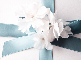 White gift box wrapped with blue ribbon and decor flowers