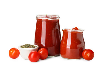 Glass jars of tasty tomato sauce and spices on white background