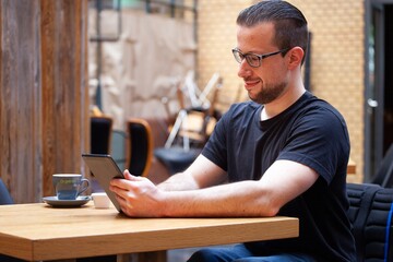 man in wheelchair looking at ipad tablet in restaurant