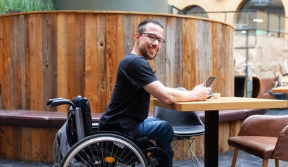 man in wheelchair looking at ipad tablet in restaurant