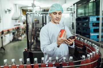 Male factory worker using digital tablet at drinks production factory.  concept inspecting production