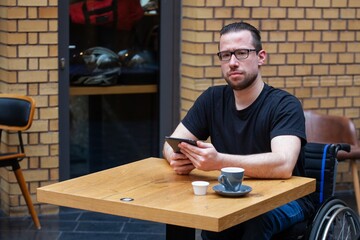 Fototapeta premium man in wheelchair looking at ipad tablet in restaurant