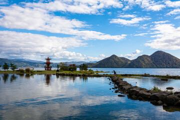 白い雲が浮かぶ青空と洞爺湖畔に浮かぶ浮見堂