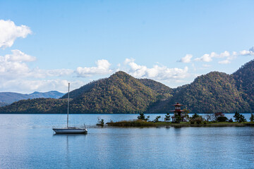 青空に浮かぶ雲と洞爺湖浮見堂のそばに浮かぶボート