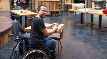 man in wheelchair looking at ipad tablet in restaurant
