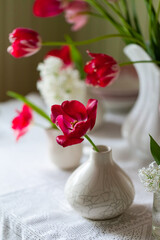Composition with beautiful bouquets of fresh pink tulips in a ceramic white porcelain vases. Summer house terrace. Green wooden background, copy space for text