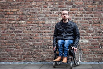 Fototapeta na wymiar man in wheelchair in front of brick wall