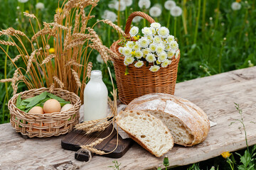 Fototapeta na wymiar Concept of natural organic products from the local farm. Homemade bread, fresh milk, eggs. Wooden background, outdoors. Close up, copy space for text
