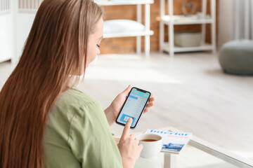 Young woman with mobile phone checking her e-mail at home
