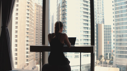 Young woman working from home office. Freelancer using laptop, phone and the Internet. Workplace in living room on windowsill. Quarantine time. COVID - 19 concept.