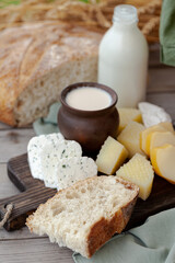 Concept of natural organic products from the local farm. Delicious homemade bread, cheese, fresh milk, cream, eggs. Wooden background, outdoors. Close up, copy space for text