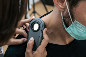 Dermatologist examines male patient birthmark with dermatoscope. Mole checkup. Close up of...