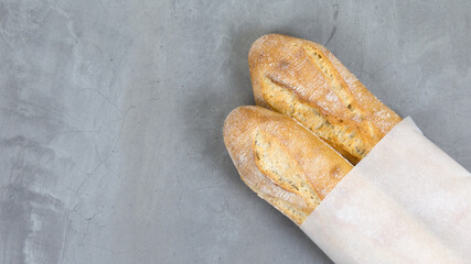 close up testy french baguettes, baked bread on grey stone table background. eco-friendly paper packaging. copy space