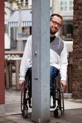 Man in wheelchair hiding behind metal post