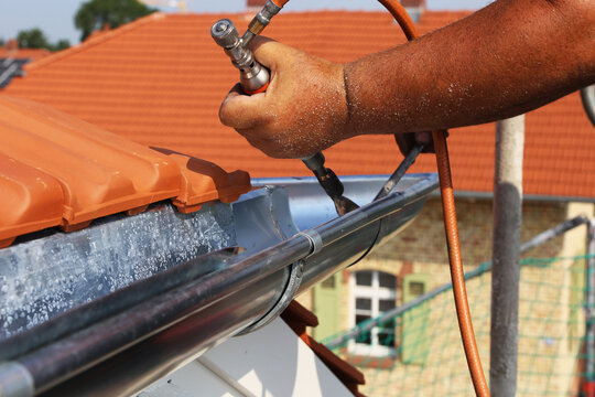 Dachdecker bei Spenglerarbeiten an einer Dachrinne
