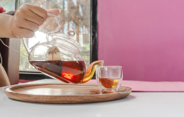 Hot black tea pouring from the pot into teacup.