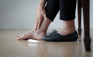 Elderly woman putting cream on swollen feet before put on shoes