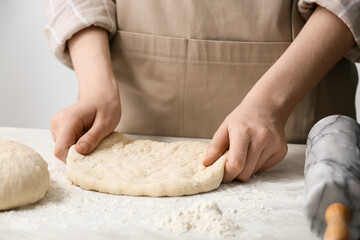 Female chef preparing dough on kitchen table, closeup