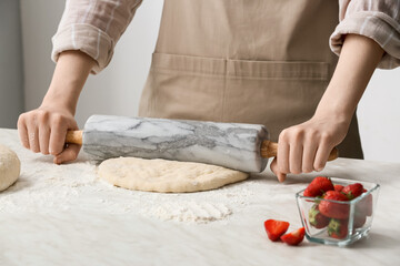 Female chef preparing dough on kitchen table, closeup